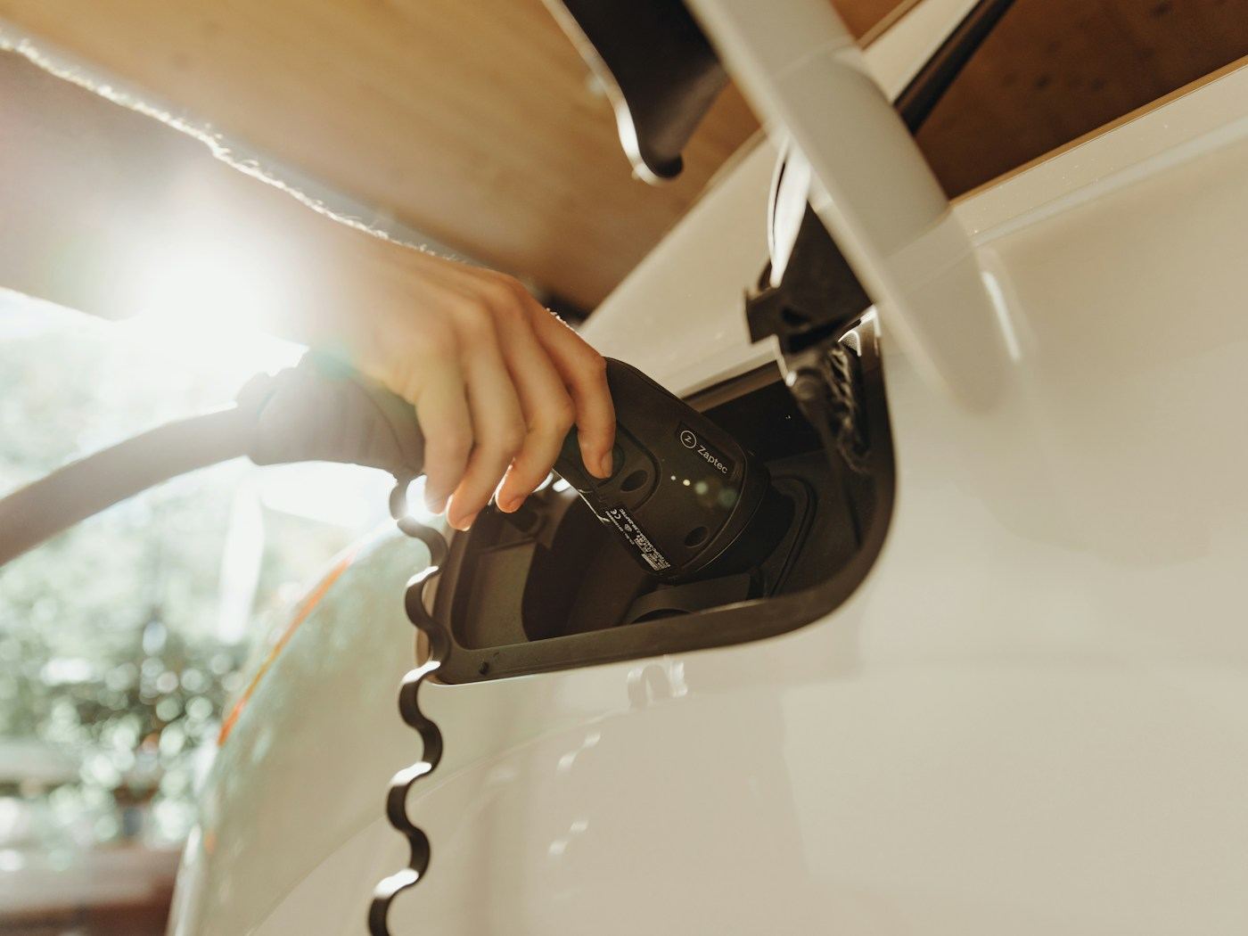 Hand plugging a Level 2 charging cable into an electric vehicle